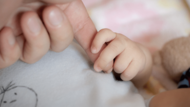 Mano adulta tomando la mano de un bebe